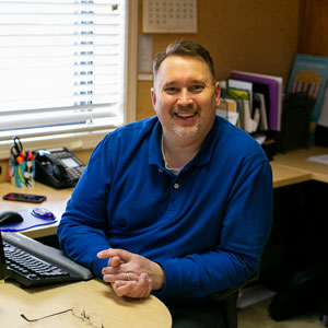 Man at desk smiling at camera